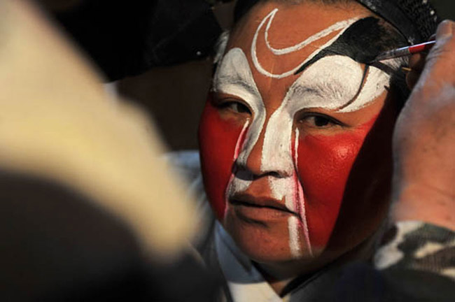 A performer puts on make-up at the back stage before singing Qinqiang Opera in Zhongning village, Ningxia Hui autonomous region on Feb. 19, 2013. (Photo/Xinhua)