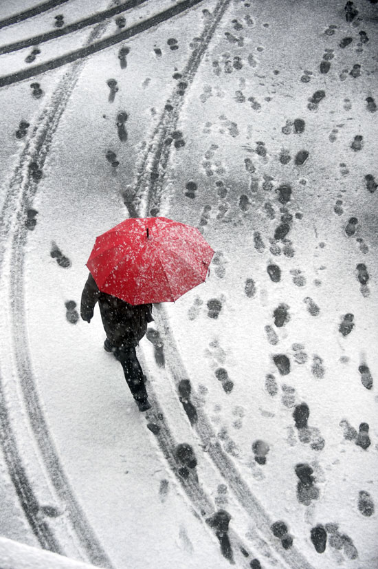 A citizen walks past a street in Hangzhou on Feb. 19, 2013. Snowstorm hit most part of Zhejiang province due to cold air influence. Local meteorological bureau had issued an orange alert for snowfall. (Photo/Xinhua)