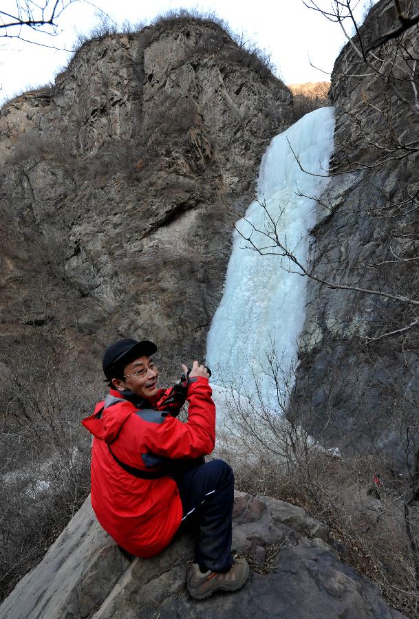 A tourist takes photos of a frozen waterfall in the Anjiazhuang Valley of Mentougou District, a suburb of Beijing, capital of China, Feb. 23, 2013. (Xinhua/Li Wenming) 