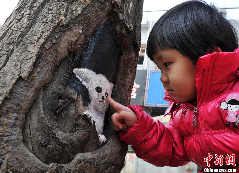 Student painter Wang Yue shows her talent by painting tree holes in Shijiazhuang, capital city of Hebei Province. (Photo/CNS)