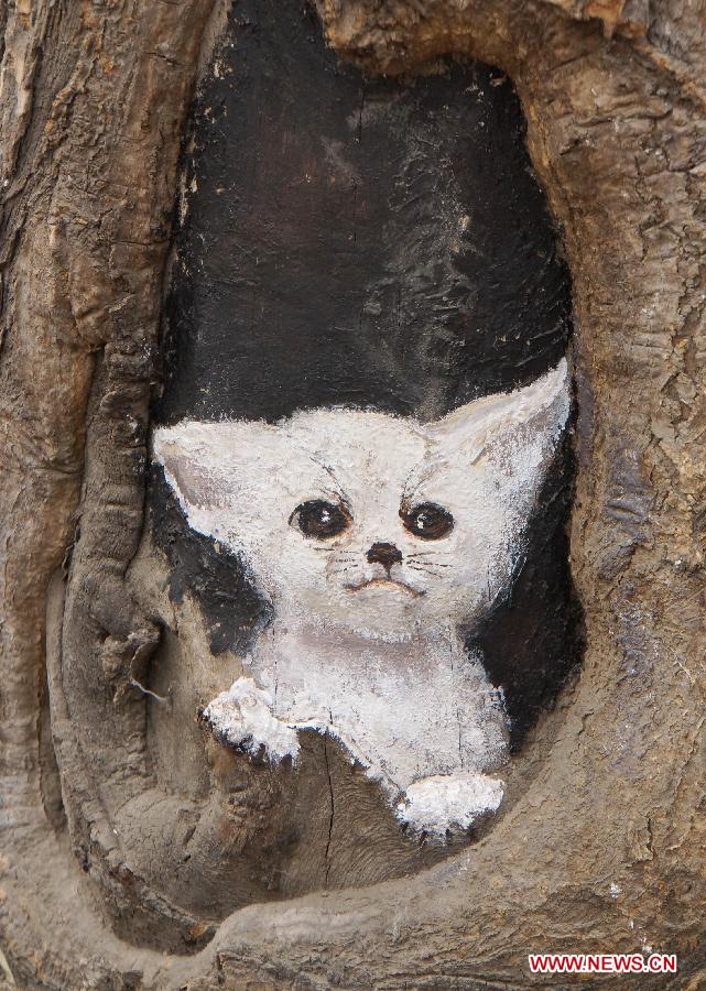 A tree hollow painting is seen at Jiuzhong street in Shijiazhuang, capital of north China's Hebei Province, Feb. 24, 2013. Paintings in shade tree hollows by Wang Yue, a local art student, became an Internet sensation lately. (Xinhua/Ding Lixin)