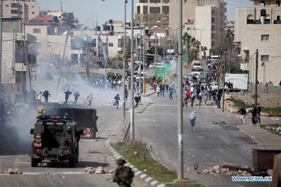 Palestinian protesters take cover from tear gas fired by Israeli soldiers during clashes outside Ofer prison near the West Bank city of Ramallah on Feb. 25, 2013. (Xinhua/Fadi Arouri) 