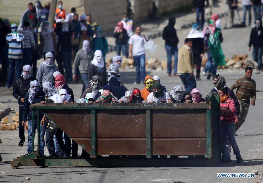 Palestinian protesters take cover from tear gas fired by Israeli soldiers during clashes outside Ofer prison near the West Bank city of Ramallah on Feb. 25, 2013. (Xinhua/Fadi Arouri) 