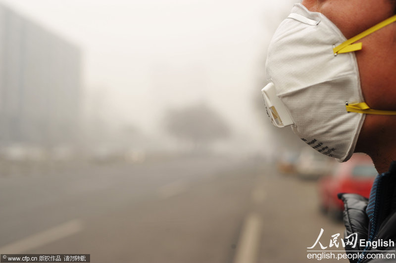 A mask-wearing man is in the sand-hit street of Beijing, Feb.28, 2013. Sand and haze hit Beijing in a row from Wednesday, causing serious air pollution and poor visibility. The Meteorological Bureau of Beijing issued blue alert for strong gale and yellow alert for haze yesterday. (Photo/CFP)