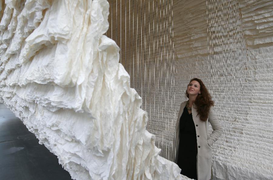 A working staff watches the monumental rice paper boat by renowned Chinese artist Zhu Jinshi during the media preview of the Art 13 London new modern and contemporary art fair at Olympia Grand Hall in London, Feb. 28, 2013. The 12-metre-long installation made of 8,000 sheets of rice paper and presented by Pearl lam Galleries was built by 20 people over three days and brought to London from Shanghai. (Xinhua/Yin Gang)