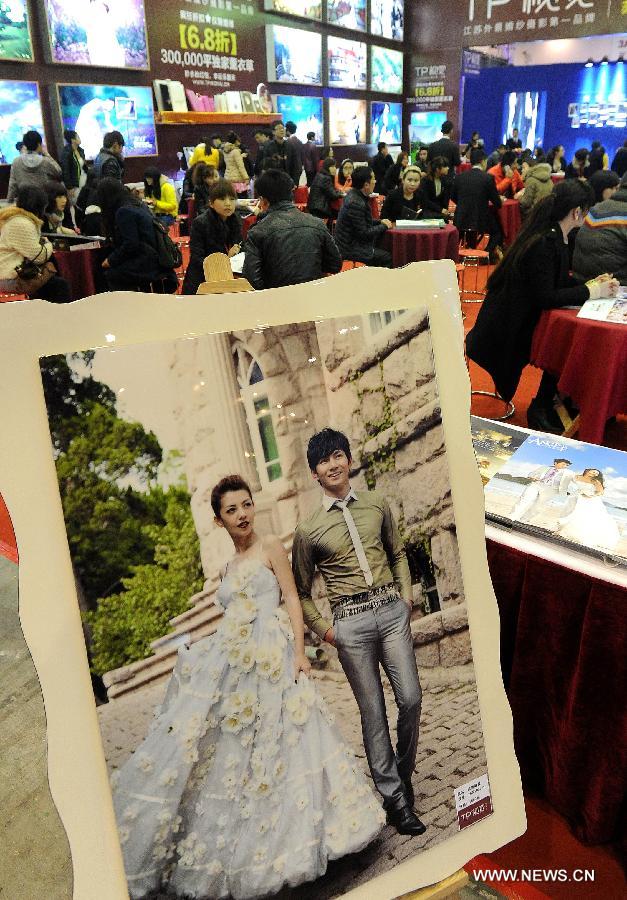 Visitors consult information on wedding photos during a wedding expo in Suzhou City, east China's Jiangsu Province, March 1, 2013. (Xinhua/Hang Xingwei)