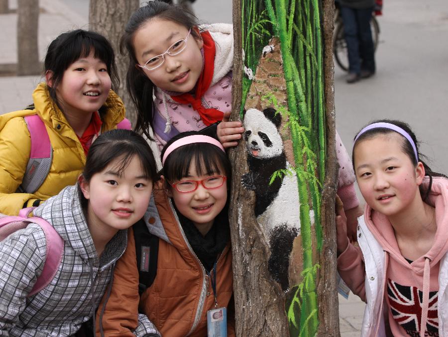 Young girls pose for photo with a tree hollow painting created by Wang Yue, a local college student, at Jiuzhong Street in Shijiazhuang, capital of north China's Hebei Province, March 1, 2013. (Xinhua/Ding Lixin) 