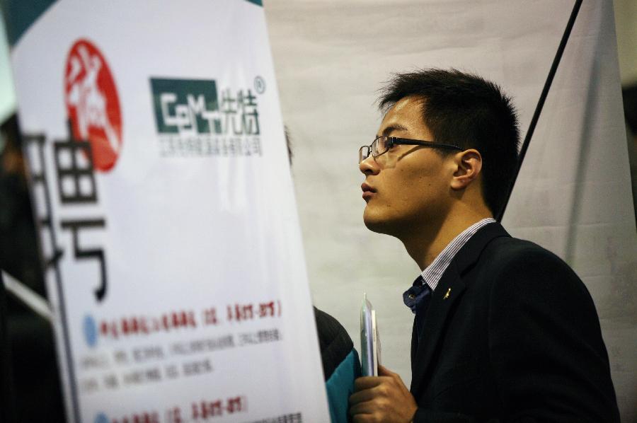 A job seeker reads employment information at a job fair in Nanjing, capital of east China's Jiangsu Province, March 2, 2013. More than 20,000 job opportunities were offered at the job fair. (Xinhua/Wang Xin)