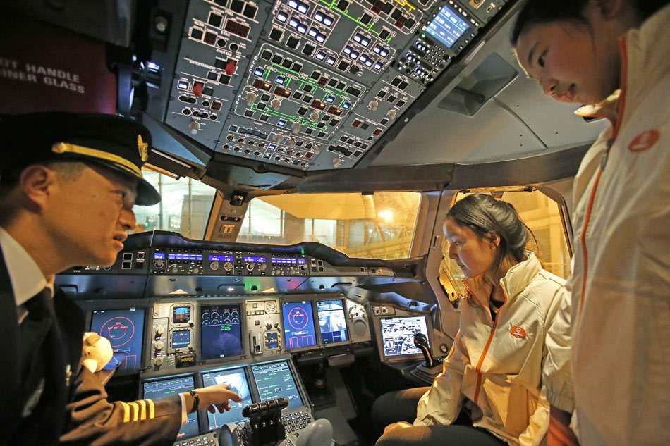 Captain of the aircraft introduces the cockpit to the children, Guangzhou, Feb. 21, 2013. The street children adopted by Light Love Family in Beijing took a Southern Air Airbus A380 flight from Beijing to Guangzhou to experience a Love journey activity organized by Airbus and China Southern Airlines. (Xinhua/Li Fangyu)