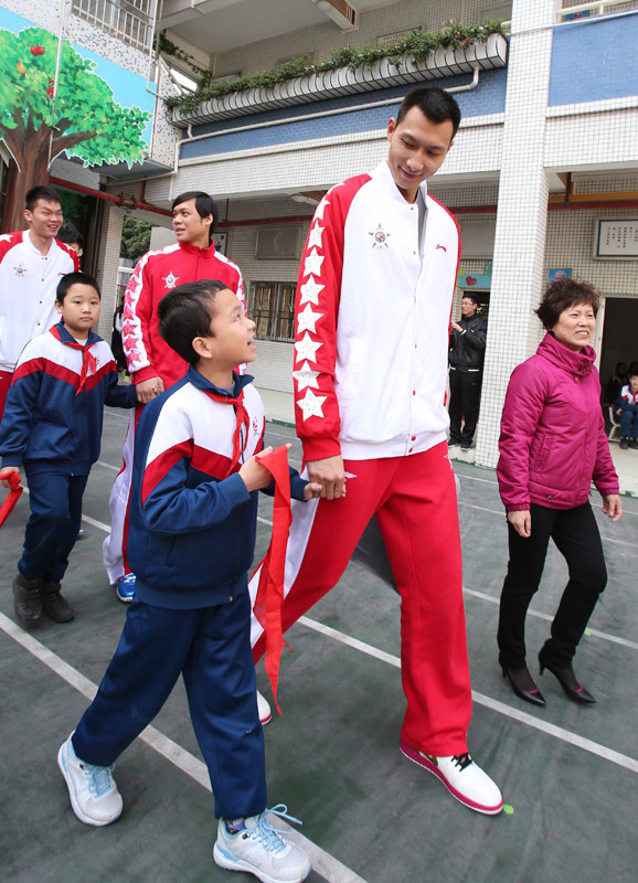 The CBA All-Star player -Yi Jianlian (second from right) walks on the campus with students on Feb. 23, 2013. The CBA All-Star Game players came to the Guangzhou Lixian Primary School to communicate with the teachers and students. (Xinhua/Meng Yongming)
