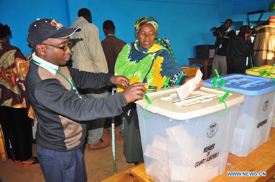 A voter (R) casts her ballot at a polling station with the help of an election staff in Gatundu, Kenya, March 4, 2013. A total of 14.3 million Kenyan voters lined up to cast their ballots Monday morning to choose the country's next president, the first after disputed presidential elections tally stirred up violence five years ago. (Xinhua/Allan Muturi) 