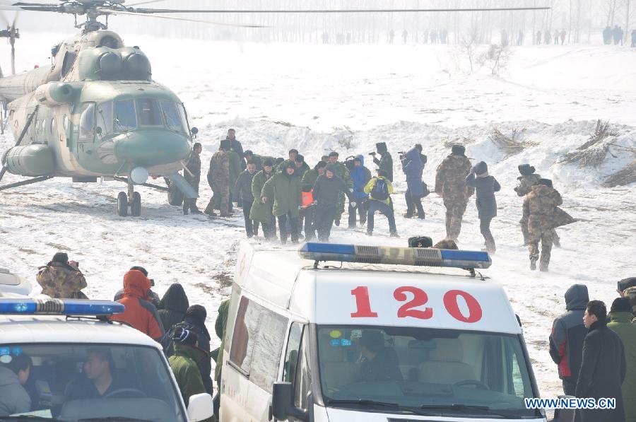 Rescued people are sent to ambulances near the Songhuajiang River, northeast China's Jilin Province, March 4, 2013. Nine people were evacuated to safety by a helicopter after three ferries carrying nine passengers were stranded for more than 28 hours in the Songhua River on Monday. (Xinhua)
