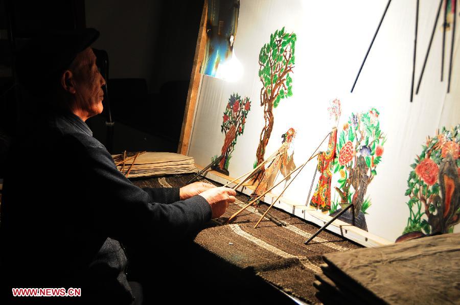 A folk artist presents Daoqing (a folk operetta originated from the chanting of Taoist scriptures) shadow play backstage in Huanxian County, northwest China's Gansu Province, late March 4, 2013. The county has made great efforts to preserve and promote the folk performing art in recent years. Huanxian now boasts 52 shadow play troupes. (Xinhua/Fan Peishen) 