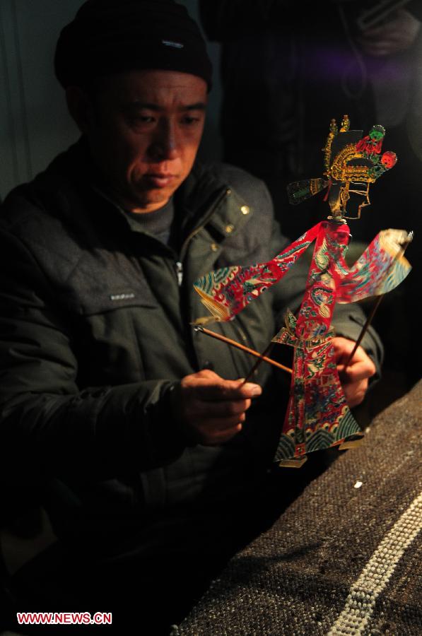 A folk artist shows a figure of Daoqing (a folk operetta originated from the chanting of Taoist scriptures) shadow play in Huanxian County, northwest China's Gansu Province, late March 4, 2013. The county has made great efforts to preserve and promote the folk performing art in recent years. Huanxian now boasts 52 shadow play troupes. (Xinhua/Fan Peishen)