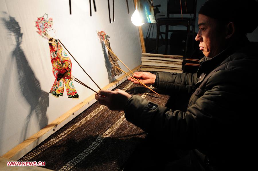 A folk artist presents Daoqing (a folk operetta originated from the chanting of Taoist scriptures) shadow play backstage in Huanxian County, northwest China's Gansu Province, late March 4, 2013. The county has made great efforts to preserve and promote the folk performing art in recent years. Huanxian now boasts 52 shadow play troupes. (Xinhua/Fan Peishen) 