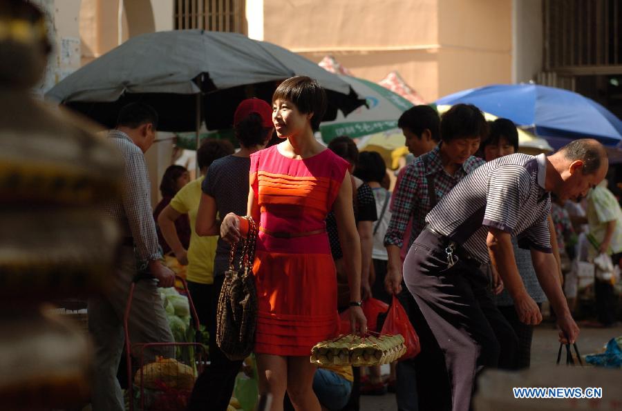 Cao Shuang (C), an airborne security guard of China South Air, buys food at a market in Sanya, southernmost China's island province of Hainan, March 4, 2013. (Xinhua/Xu Qintao)