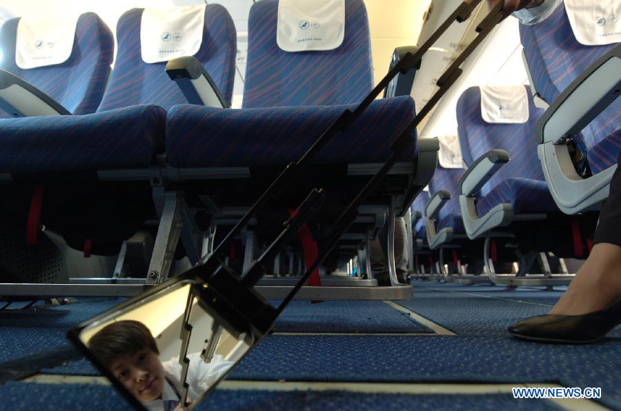 Cao Shuang, an airborne security guard of China South Air, performs security check on an airliner at the Phoenix International Airport in Sanya, southernmost China's island province of Hainan, March 4, 2013. (Xinhua/Xu Qintao) 