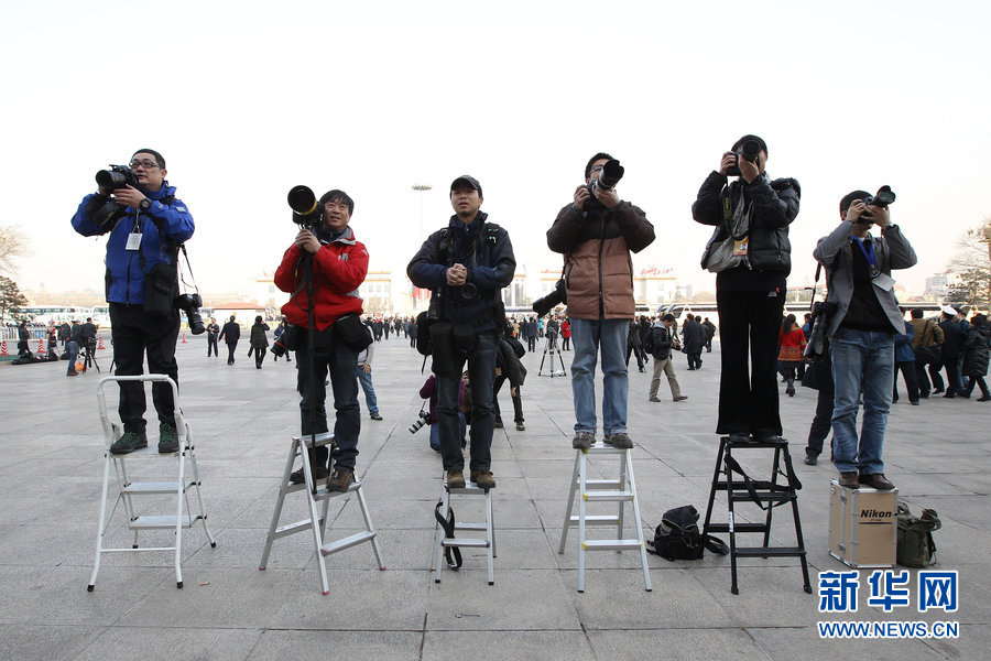 Photographers hold their professional cameras on ladders waiting for delegates.(Xinhua)