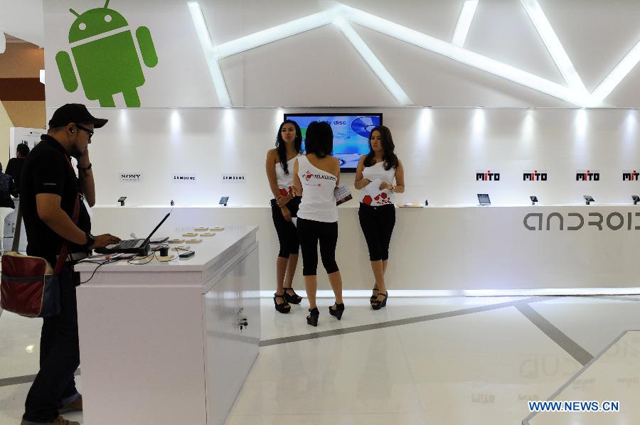 Show girls talk while a visitor tries on a computer at a booth during Mega Bazar Computer 2013 at Jakarta Convention Center, Jakarta, Indonesia, March 6, 2013. Indonesian Computer Entrepreneurs Association (Apkomindo) revealed that this year's computer tablet PC market was expected to rise 60 percent by the end of the year. (Xinhua/Veri Sanovri)