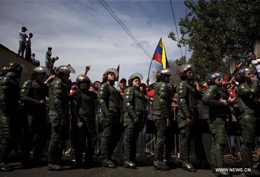 Members of the military escort Venezuelan National Guard hold a security fence during the funeral procession in honor of Venezuelan President Hugo Chavez on the streets of Caracas, capital of Venezuela, on March 6, 2013. On Tuesday afternoon, Venezuelan President, Hugo Chavez, died after fighting for almost two years with a cancer disease. The body of Chavez is moved from the health center to the Military Academy in southern Caracas, inside Tiuna's Fort. (Xinhua/David de la Paz)