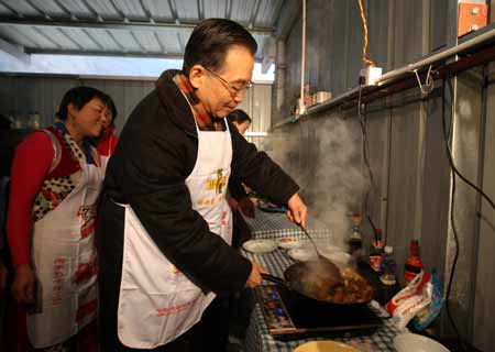 Chinese Premier Wen Jiabao (R) cooks at a kitchen shared by several families at the prefabs in Yingxiu Township of Wenchuan County, southwest China's Sichuan Province, Jan. 25, 2009. Wen Jiabao came to the quake-hit counties of Beichuan, Deyang and Wenchuan in Sichuan Province on Jan. 24 and 25, celebrating the Spring Festival with local residents.(Xinhua File Photo/Yao Dawei)