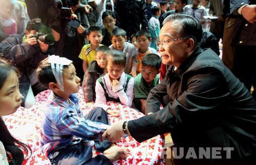 Wen Jiabao holds the hand of an injured boy in Mianyang, southwest China's Sichuan Province on May 13, 2008 after the 8.0 magnitude earthquake hit the area a day earlier.(Xinhua File Photo)