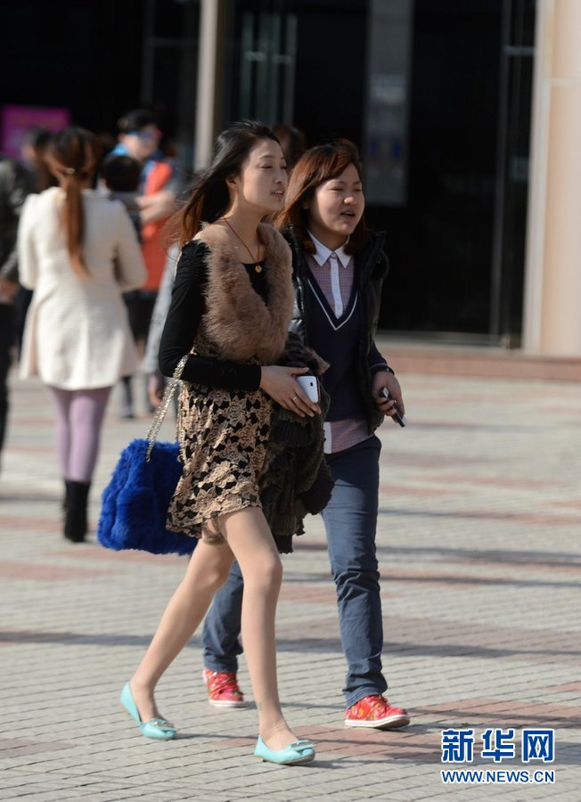 Pedestrians wear spring and even summer clothes on the street of Yangzhou on Mar. 6, 2013. The temperature reached 22 degrees Celsius (Photo/Xinhua)