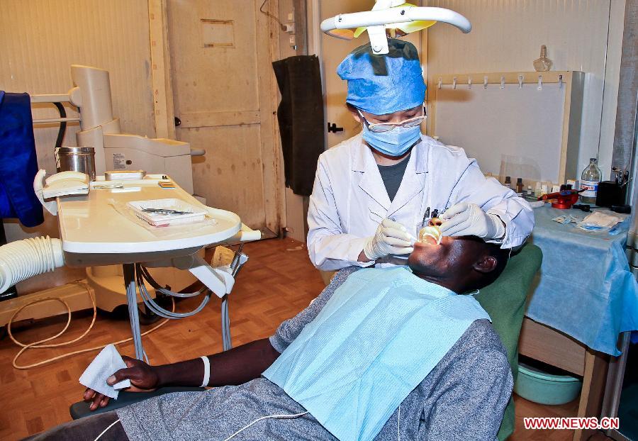 Duan Xiaoyan, a dentist of the medical team of the 14th batch of Chinese peacekeeping force for Liberia, provides treatment for a UN staff member in Zwedru, Liberia, March 8, 2013, the International Women's Day. There are 13 females among the 43 members of the medical personnel group. (Xinhua/Gao Lei)