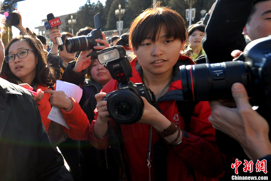 A female journalist covering the NPC and CPPCC sessions takes photos. (Photo/CNS)