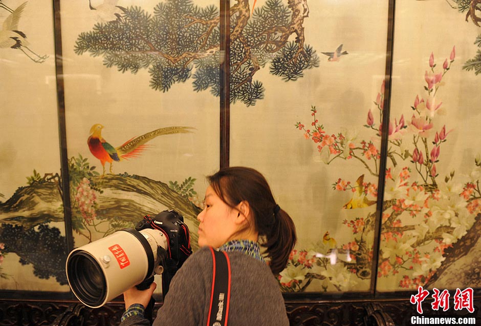 A female journalist covering the NPC and CPPCC sessions takes photos. (Photo/CNS)