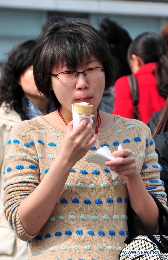 A girl eats an ice-cream cone on a street in Beijing, capital of China, March 8, 2013. The highest temperature of Beijing hit this year's new high to 19 degrees Celsius on March 8. (Xinhua/Chen Yehua)