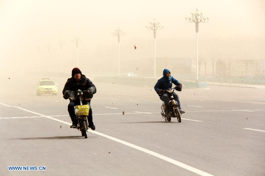 Bikers brave wind and sand on a road in Bazhou, north China's Hebei Province, March 9, 2013. A cold front brought strong wind as well as sand and dust to most part of north China region on March 9. (Xinhua/He Huaqiao)