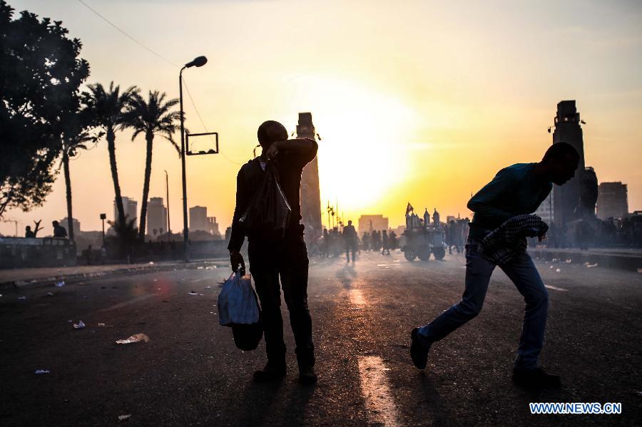 Egyptian protesters take cover from teargas during clashes between anti-government protesters and riot police near Tahrir square in Cairo, March 9, 2013. Two protesters were killed during the clashes. (Xinhua/Amru Salahuddien) 