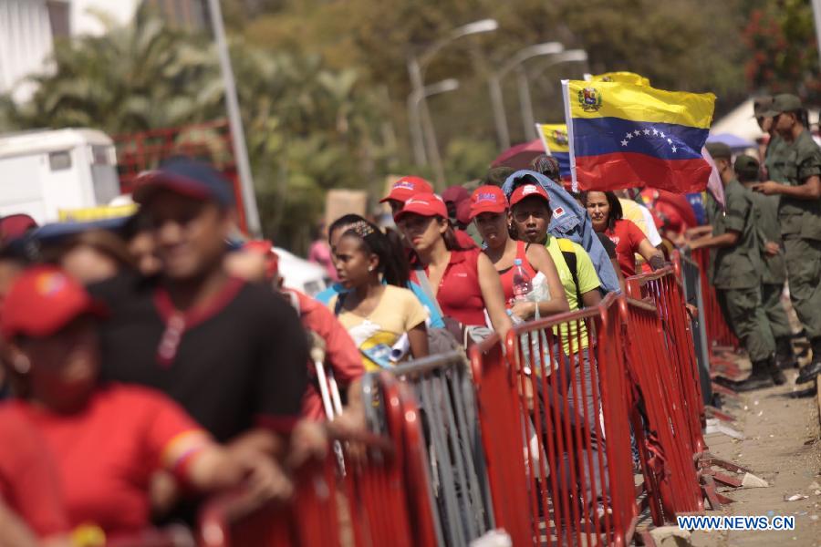Residents hold Venezuelan flags as they wait in the Proceres Avenue to enter the Military Academy of Venezuela to say their last goodbye to President Hugo Chavez, in the city of Caracas, capital of Venezuela, on March 9, 2013. (Xinhua/AVN)