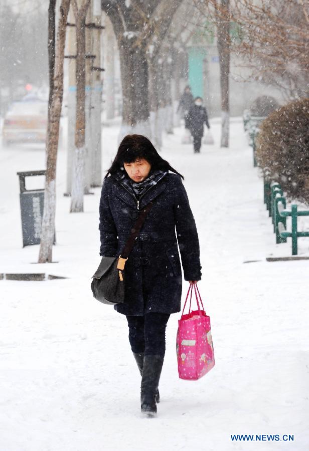 A pedestrian walks on a snow-covered street in Harbin, capital of northeast China's Heilongjiang Province, March 9, 2013. Local meteorological bureau issued a blue alert against heavy snowfall on Saturday morning. (Xinhua/Wang Song) 