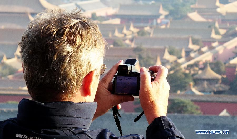 A foreign tourist takes photo of the Forbidden City from the Jingshan Park in Beijing, capital of China, March 10, 2013. As the weather turned warmer, many tourists from both home and abroad came to Beijing to visit. (Xinhua/Li Xin)  