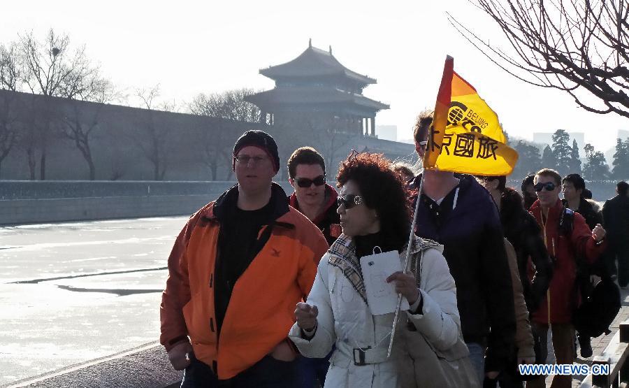 Tourists walk along the moat of the Forbidden City in Beijing, capital of China, March 10, 2013. As the weather turned warmer, many tourists from both home and abroad came to Beijing to visit. (Xinhua/Li Xin)  