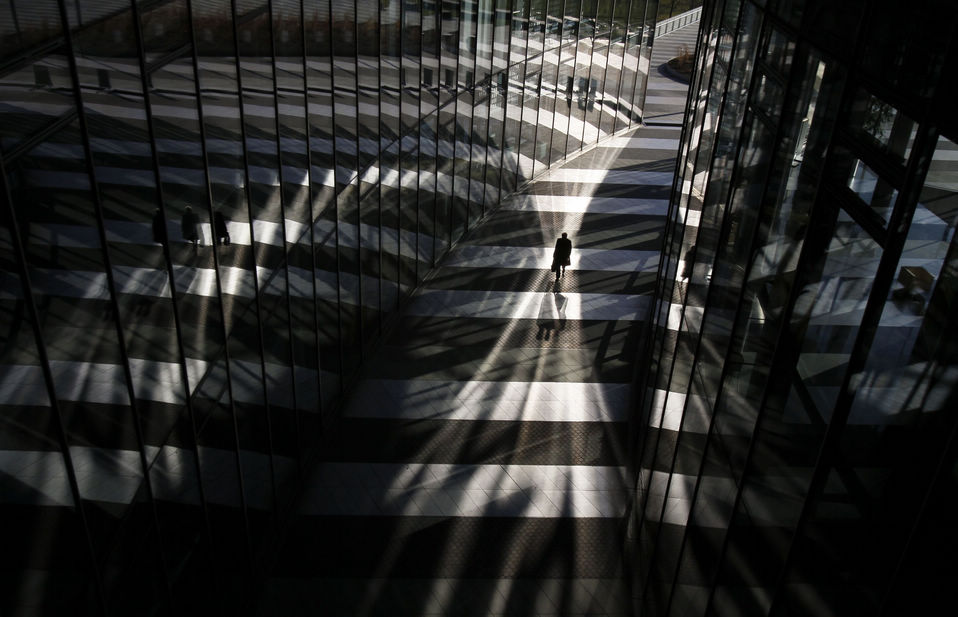 A man walks between glass facades of the Bonn Post Tower, the headquarters of German postal and logistics group Deutsche Post DHL in Bonn on March 5, 2013. (Xinhua News Agency/Reuter) 