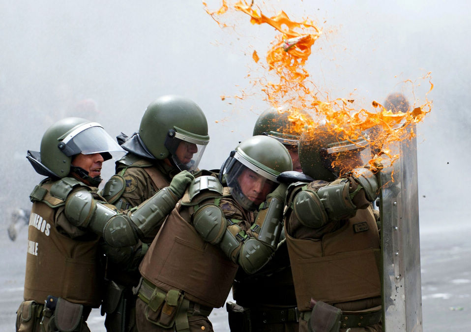 Chilean riot policemen protect themselves with shields during clashes with students at a protest in Santiago, Chile, Thursday. The students demanded the government of Chilean President Sebastián Piñera to improve the public education system. (Xinhua News Agency/AFP)