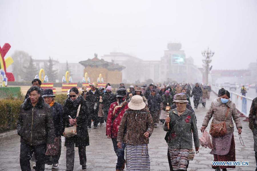 People walk in snow in Lhasa, capital of southwest China's Tibet Autonomous Region, March 11, 2013. (Xinhua/Liu Kun)