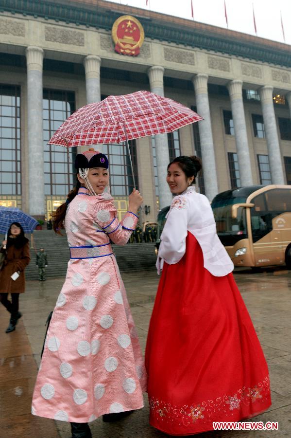 Staff members dressing in costumes of ethnic minorities walk to the Great Hall of the People in Beijing, capital of China, March 12, 2013. The closing meeting of the first session of the 12th CPPCC National Committee is to be held in Beijing on Tuesday. (Xinhua/He Junchang)  