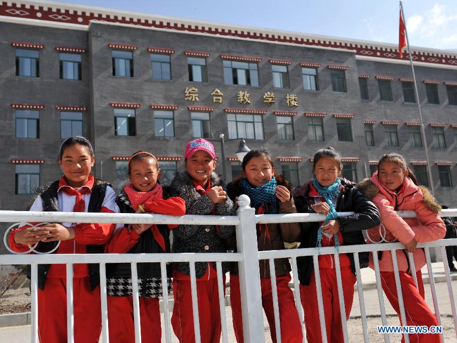 Pupils of the Tibetan ethnic group pose for photos in front of a Tibetan-style teaching building at No. 1 Primary School of Deqin County in Diqing Tibetan Autonomous Prefecture, southwest China's Yunnan Province, March 12, 2013. A total of 1,260 pupils, most of whom are of the Tibetan ethnic group, study at this school, which was founded in September 2012. Pupils here are offered free meals and lodging. (Xinhua/Lin Yiguang) 