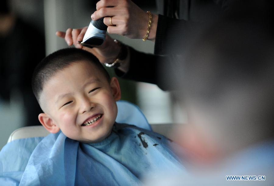 A boy smiles as having his haircut at a barbershop in Shenyang, capital of northeast China's Liaoning Province, March 13, 2013, on the occasion of the second day of the second lunar month, known in Chinese as Er Yue Er, "a time for the dragon to raise its head", as a Chinese saying goes. Barbershops across the country opened early to begin one of their busiest days of the year, as many Chinese hold the superstitious belief that getting a haircut at a time when the "dragon raises its head" means they will have a vigorous start to the new year. (Xinhua/Zhang Wenkui)