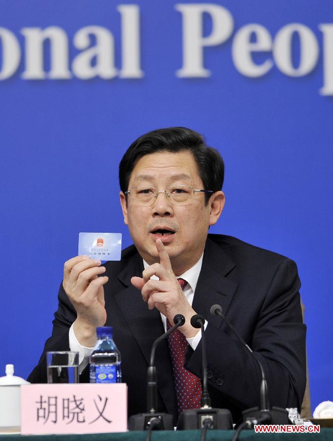 Hu Xiaoyi, vice minister of human resources and social security, who is also deputy director of the health reform office of the State Council, shows a social security card while answering questions at a press conference on medical and healthcare system reform held by the first session of the 12th National People's Congress (NPC) in Beijing, capital of China, March 14, 2013. (Xinhua/Wang Peng)