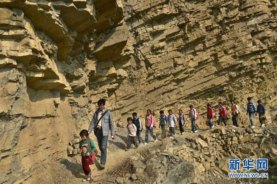 Xu Liangfan, principal of Banpo School, guides the students through the rugged path to the school on March 11, 2013. (Xinhua/Peng Nian)