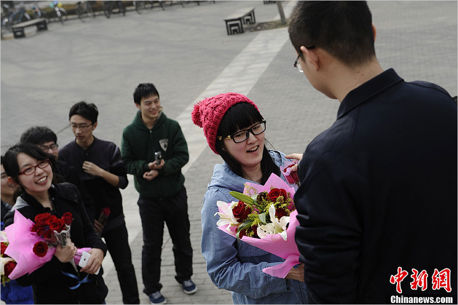 A Tsinghua University student sends flowers to his classmate to celebrate "Ladies' Day" on March 7, one day before "Women's Day" on March 8, 2013. Data issued by China's National Bureau of Statistics indicates that there will be 24 million more unmarried men than women by the end of 2020. (Photo/news.china.com.cn) 