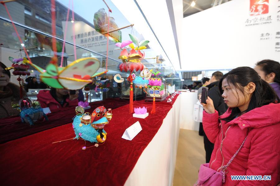 Visitors watch creative tourism commodity designs during the 2013 China International Exhibition for Caravanning, Motoring, Tourism (CMT China) in Nanjing, capital of east China's Jiangsu Province, March 15, 2013. The three-day exhibition, with the participation of 289 exhibitors from 28 countries and regions, opened in Nanjing Friday. (Xinhua/Shen Peng) 