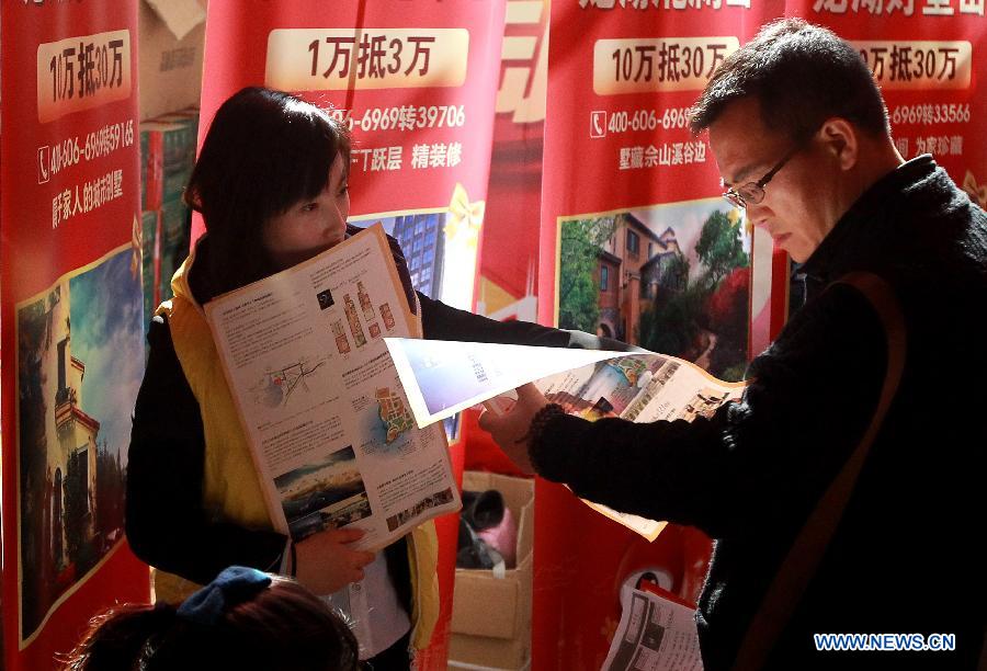 A staff member (L) of a property developer introduces their houses to a man at a real estate expo in east China's Shanghai Municipality, March 15, 2013. The expo lasts from March 15 to March 18. (Xinhua/Pei Xin)