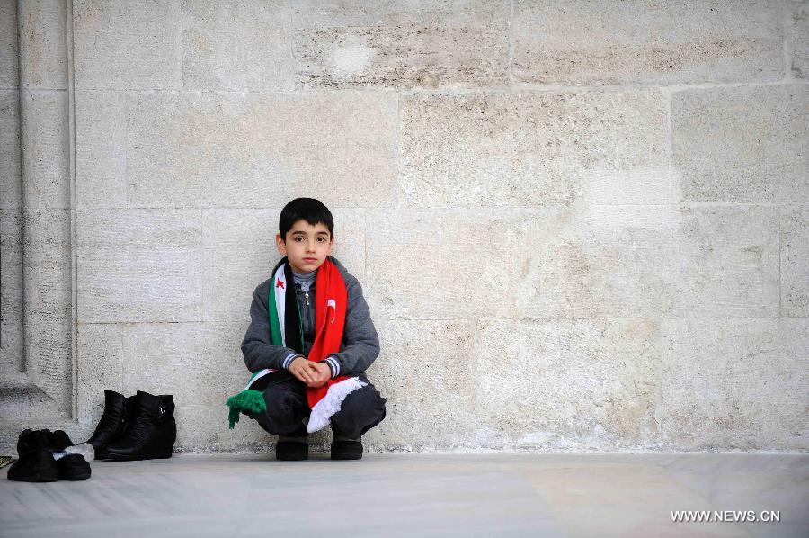 A boy waits for his mother who is praying before a demonstration in Istanbul, Turkey, on March 15, 2013. More than 1,000 Turks and Syrians held a rally in Turkey's Istanbul city in protest of the Syrian government on Friday, two years after the unrest broke out in Syria. (Xinhua/Ma Yan) 