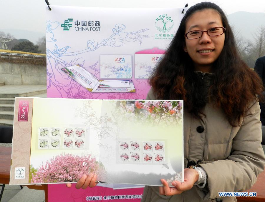 A stamp collector presents the "peach blossom" stamps at the Beijing Botanical Garden in Beijing, capital of China, March 16, 2013. China Post published a set of "peach blossom" stamps on Saturday. (Xinhua/Wang Zhen)  